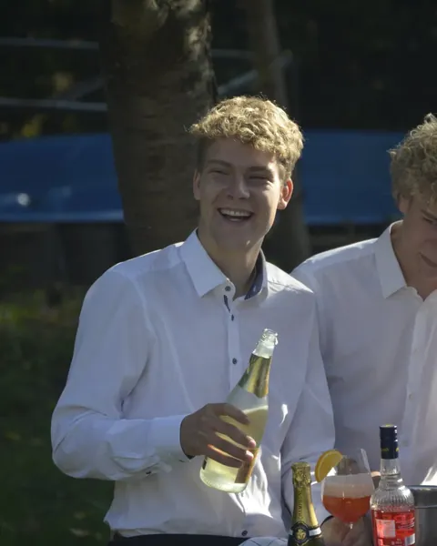 Henning lacht und hält eine Sektflasche