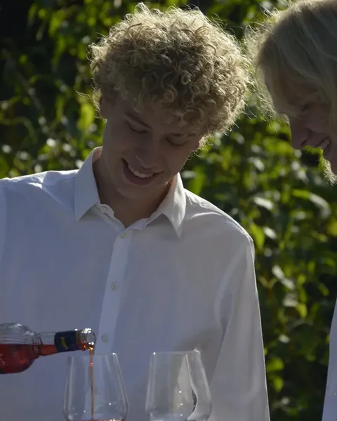 Lutz gießt lächelnd Aperol in ein Weinglas